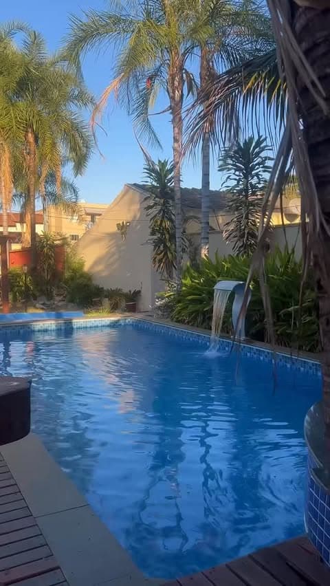 Vista ampla da piscina com deck e vegetação tropical